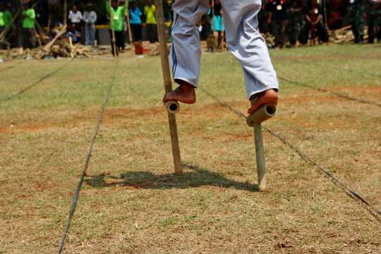 A participant plays traditional bamboo stilts outdoors, highlighting balance, agility, and Indonesian cultural games.