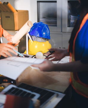 Two technicians inspect server racks in data center with tablet and fiber optic cable. Engineer and specialist discuss maintenance work in data center. Man and woman work together with safety equipmen