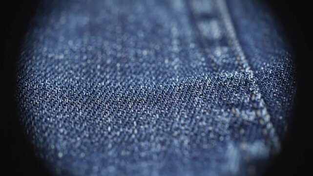 Close up view of dark blue denim fabric with intricate texture and stitch detailing
