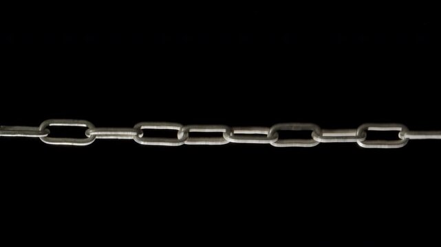 A metal chains get tension horizontally on a black background