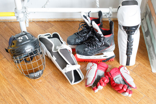 Hockey gear placed on the floor in a training area with various equipment including skates, gloves, and a helmet