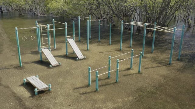 Flooded outdoor workout playground on Yenisei River embankment during spring flood and high water level in central Krasnoyarsk