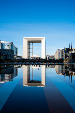 Grande Arche stands across still water in La Defense Paris France, balancing business district architecture with urban skyline reflection