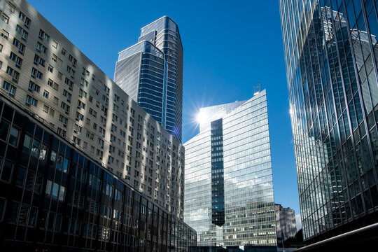 Reflective glass pulls a street canyon through La Defense Paris France, where skyscraper architecture compresses the urban business district