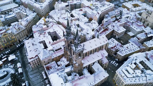 Aerial drone footage of a historic church in Prague covered in snow during winter.