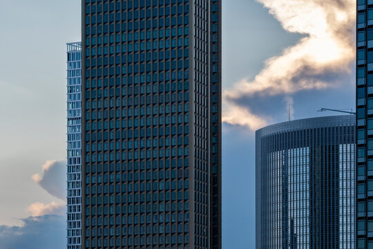 Clouds glow behind Frankfurt Germany skyscrapers, where glass office towers give business district architecture dramatic urban contrast