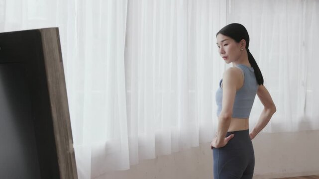 Asian Woman in Yoga Wear Checking Body Shape in Mirror