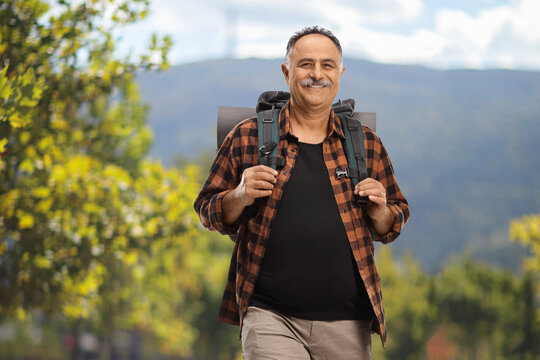 Mature hiker carrying a backpack and walking in a park
