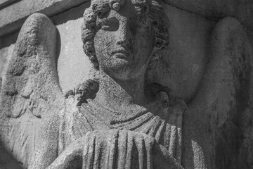 Fototapeta premium Ancient angel statue with stern expression in monochrome style