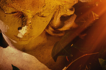 Fototapeta premium Dramatic close up of ancient angel statue in warm golden sunlight, symbolic image of sorrow, peace and eternity