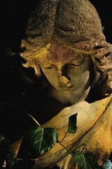 Fototapeta premium Dark gothic angel statue illuminated by dramatic golden light, symbolic image of sorrow, death and spiritual silence