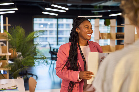 Happy curvy black businesswoman talking to colleague with copy space