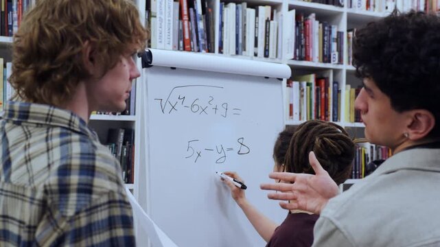 Two curly-haired male students and their dreadlocked female partner work together to solve a challenging algebraic problem. 