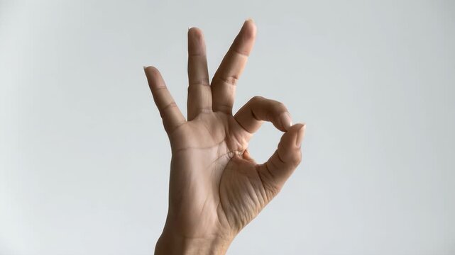 柔らかな光の中で丸いジェスチャーを作る女性の指先が映えるシンプルな背景表現