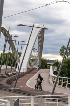 On a Lyon bridge, a cyclist follows a curved lane beside structure and railing, turning street commute and mobility into a riverfront scene.