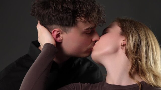 Intimate connection and romantic love, a young couple embracing with affectionate gestures against a dark background. This footage is projects exploring themes of romance, relationships, and human emo