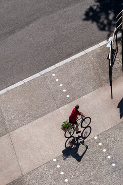 A cyclist on a bicycle moves through a Lyon lane, where shadow, pavement dots, intersection markings and delivery mobility define the road.