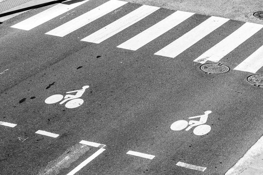 Monochrome asphalt turns a Lyon crosswalk, bicycle symbols, lane marking and intersection into a graphic study of street mobility.