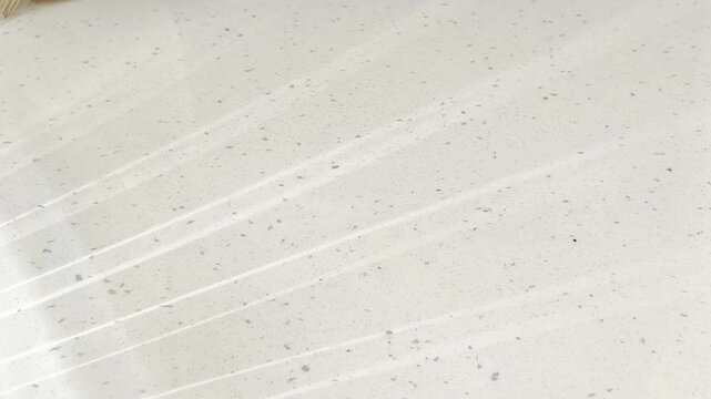Water caustic light reflections dancing on a white speckled surface creating a mesmerizing abstract background, capturing a peaceful and clean aesthetic for visual projects