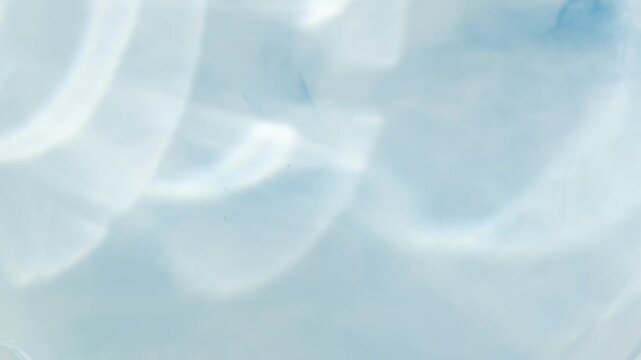 Calming caustic light reflections dancing on a pastel blue surface, creating a tranquil and mesmerizing background of pure water ripples and abstract shiny patterns