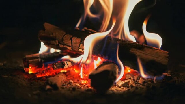 Glowing embers heating split logs, producing flickering blue and orange flame tongues at hearth