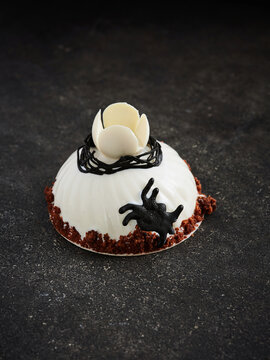 This dessert features a chocolate mousse dome with artistic decorations such as a flower and a cat figure