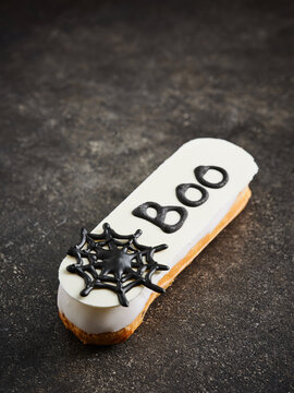 The eclair features a white icing with the word Boo and a spider design on top. This dessert is ideal for Halloween parties, events, and themed menus