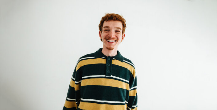 Young man with smartphone smiling in studio portrait for mobile communication and social media