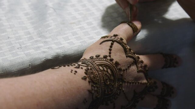 Closeup brown henna stain drawn onto thumb of woman's hand, body art