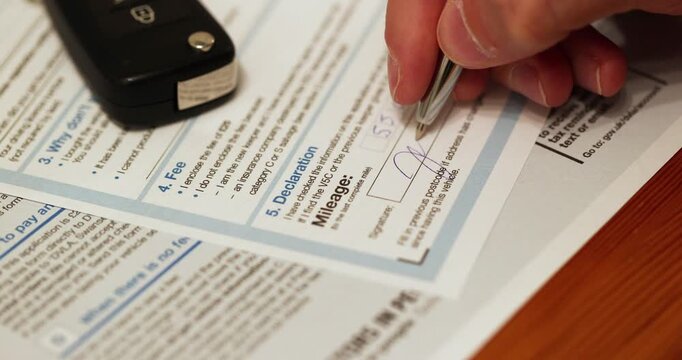 Perspective shot of accepting with mileage and signature the V62 application for a registration certificate form.