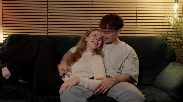 A young couple s intimate connection and affectionate moments, showcasing their happiness and bond while relaxing on a sofa during a cozy evening at home. This footage is projects related to love, rel