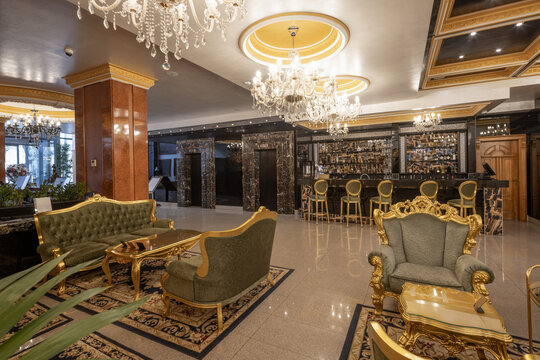 Opulent hotel lobby bar with green velvet sofas and chandeliers
