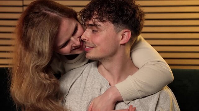 Love and connection between a young couple. A woman embraces a man from behind, both smiling and looking at each other with affection, commercial and editorial projects focusing on relationships, happ