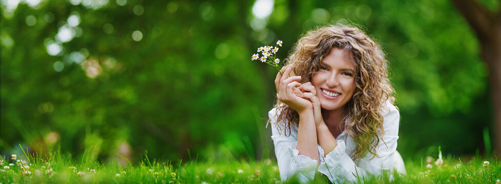 Pretty smiling authentic girl with camels flowers relaxing outdoor in summer by sunlight. Big banner with copy space.