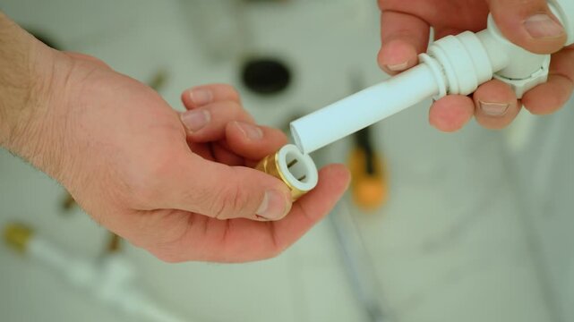 Attaching plastic pipe to brass threaded adapter, bridging materials in plumbing installation. Hand aligning push fit tubing with metal coupling, DIY water supply connection process. Joining polymer