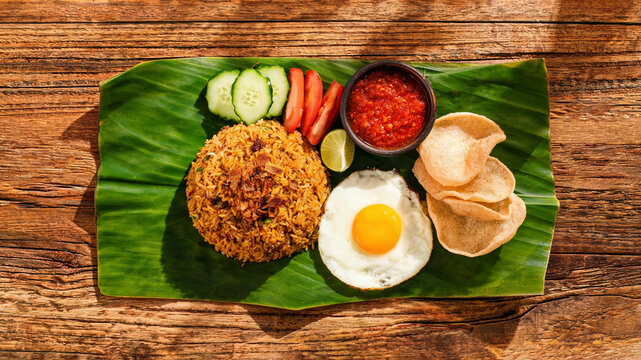 Experience the vibrant colors and textures of traditional Indonesian fried rice, beautifully presented with garnishes on a rustic wooden table