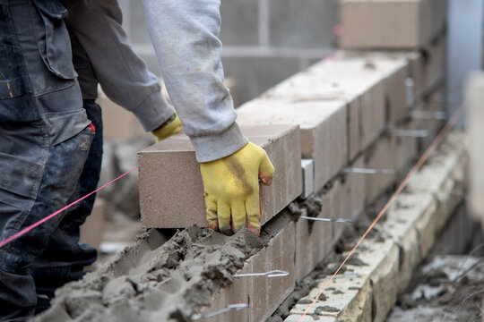 Builder works on brick wall construction in a residential area during daylight hours