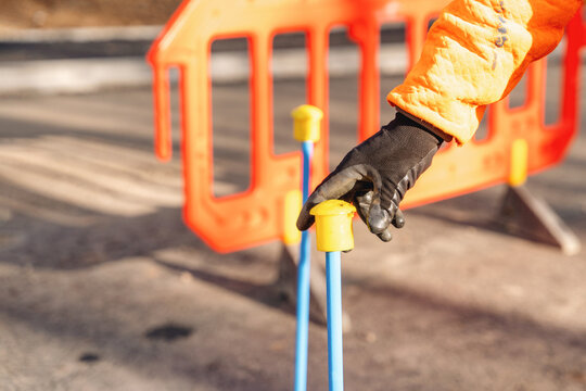 Worker sets up safety barrier on a construction site during daytime in an urban area