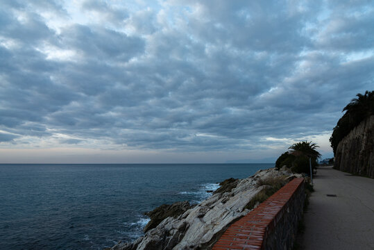 Panoramic view of the coastline of mediterranean sea near the village of Varazze, Liguria, Italy. The pedestrian promenade on the right, and the calm waters of mediterranean sea on the left. With dram