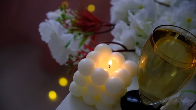 Cozy room, a burning candle casts a warm light on a bouquet of pristine white flowers, flute of champagne. Fairy lights twinkle softly, adding a touch of magic to the serene scene. Moment of quiet