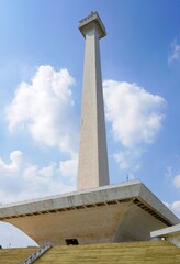 Obraz premium the National Monument (locally known as Monas or Monumen Nasional), an iconic obelisk soaring into a blue sky with scattered clouds