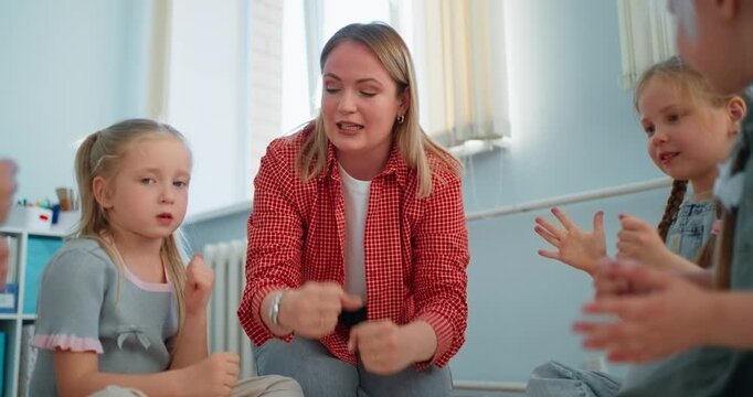 Engaged teacher guiding young children in a bright classroom, using hand gestures during an interactive early learning activity