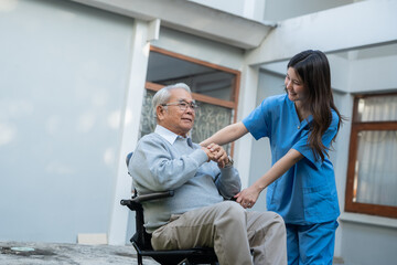 Fototapeta premium Elderly man in wheelchair interacts with caregiver in blue scrubs. Professional caregiver assisting happy senior couple, concept of retirement planning and life insurance security.