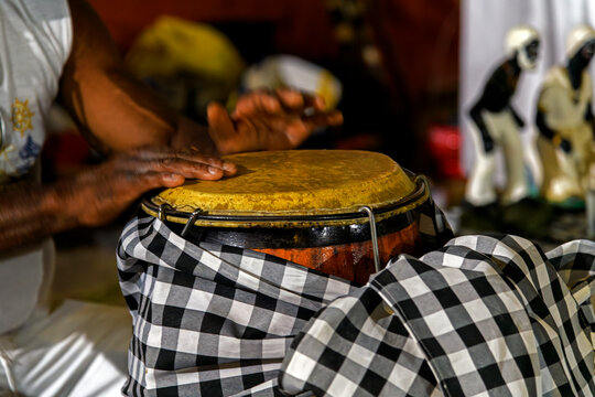 A drummer playing a traditional atabaque drum decorated with cloths during an Umbanda celebration in Brazil.