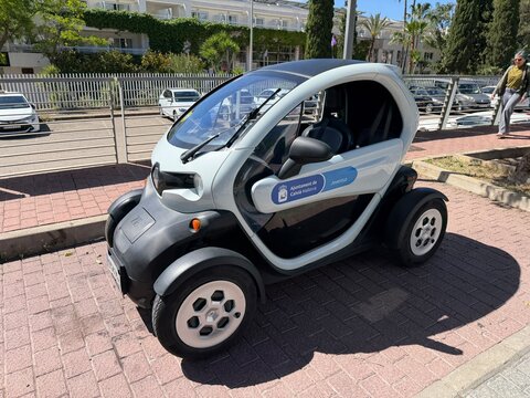 Calvia, Spain - May 16, 2026: Electric microcar parked on a city street with modern architecture and palm trees in the background, showcasing urban mobility