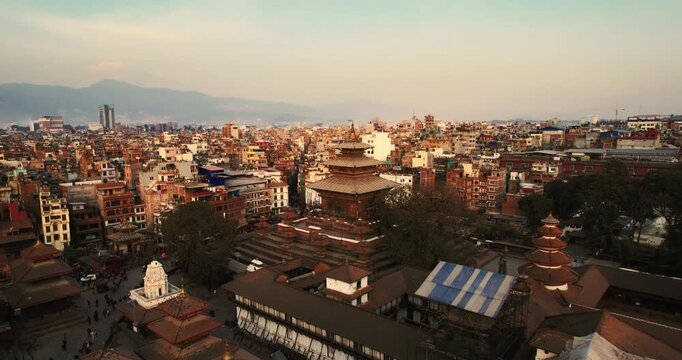 Aerial drone view of Basantapur Durbar Square showing pagoda temples and crowds gathered in the heritage plaza, with the distant Himalayan ridge fading into morning haze.
