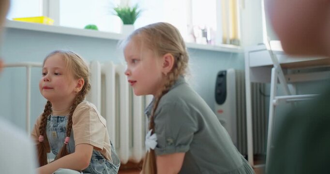 Young schoolchildren sit in a bright classroom circle, two braided girls listening and reflecting during a calm group learning activity