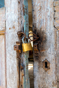 Old wooden door with a yellow padlock and rusty chain on display in an abandoned building