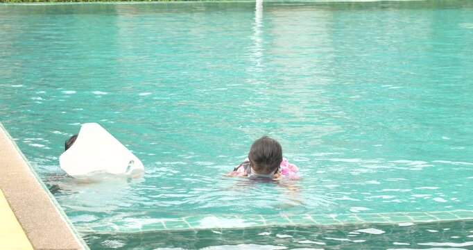 Adorable asian school kids boy and girl enjoy swim practice in resort village swimming pool