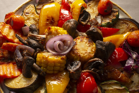 Warm roasted vegetable platter with corn, mushrooms, peppers and eggplant, charred edges and glossy olive oil glaze, served